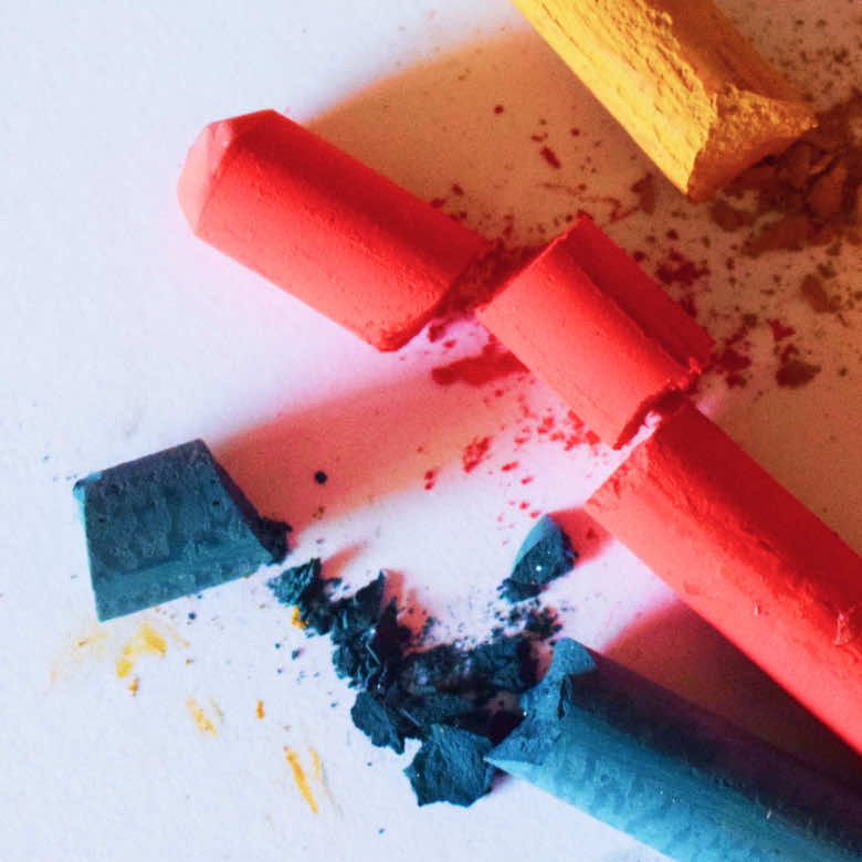 Colourful chalk crayons smashed on a white background